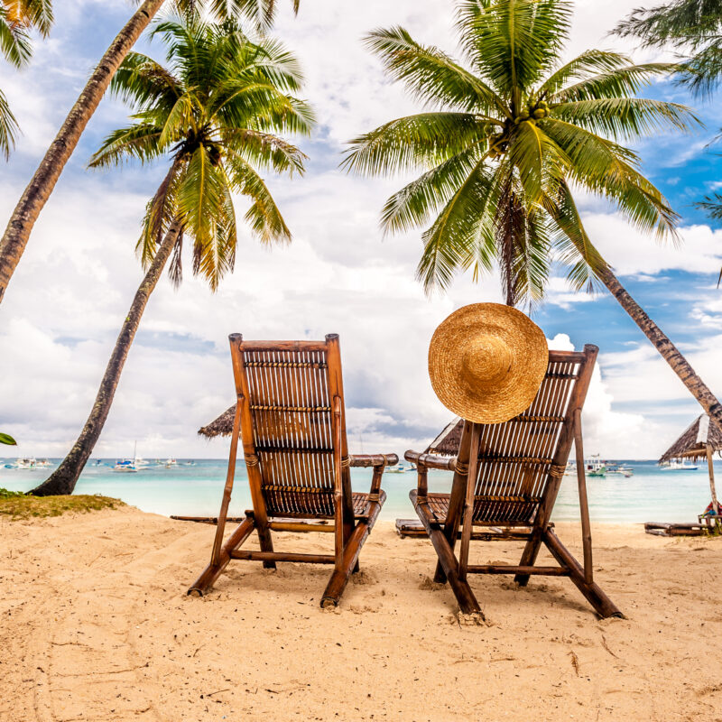 A beach with two chairs and palm trees. A representation of the benefits of a Florida Depression Treatment Center.