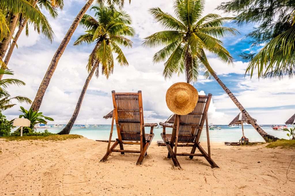 A beach with two chairs and palm trees. A representation of the benefits of a Florida Depression Treatment Center.