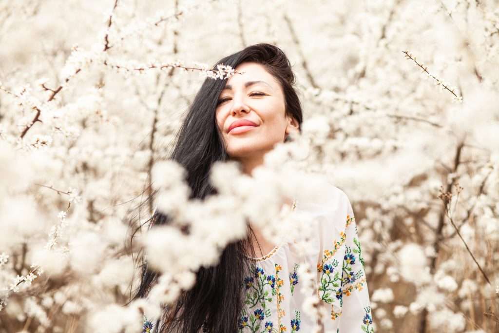 A woman experiencing the pros of a mental health therapist my smelling cherry blossoms.