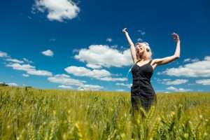 A woman listening to music in a field after hearing the answer to the question: do mental health days improve grades.