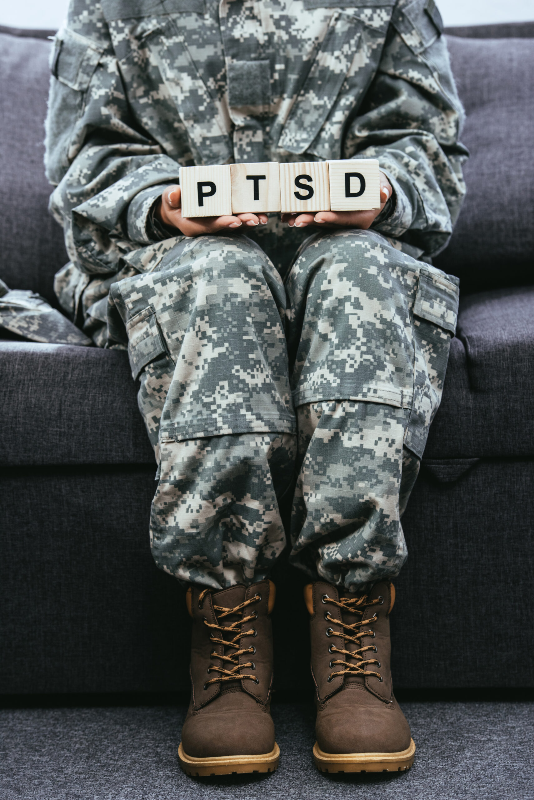 A woman in uniform holding a sign that says "PTSD" while suffering from the highest stage of PTSD